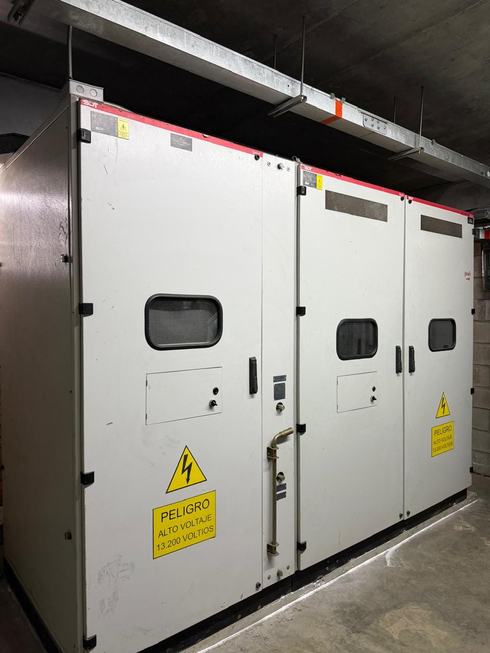 Celda de media tensión de tres módulos instalada en el sótano de un edificio, con avisos de peligro de alto voltaje a 13.200 voltios.