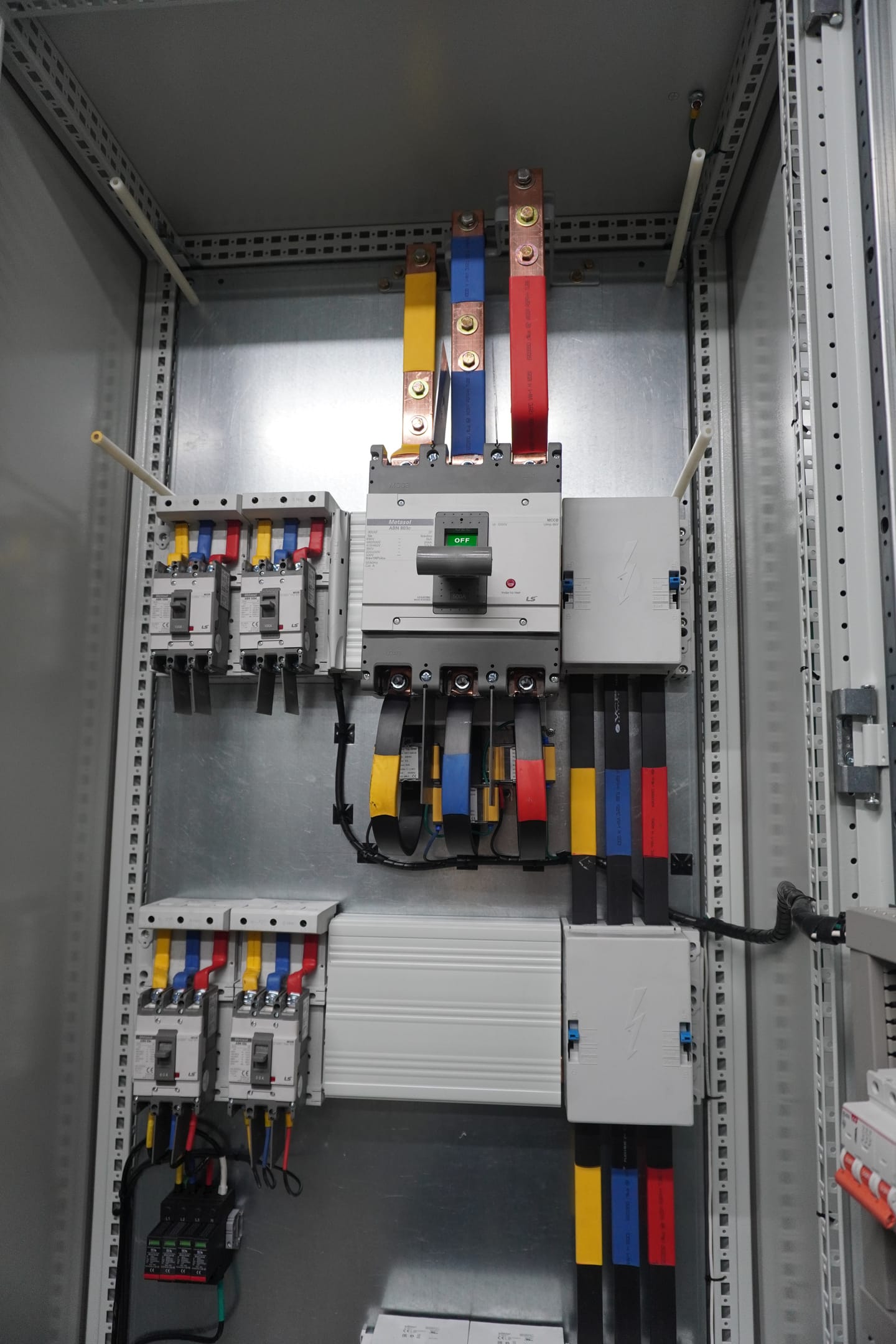 Interior de tablero con interruptor de caja moldeada y barrajes marcados por fase.