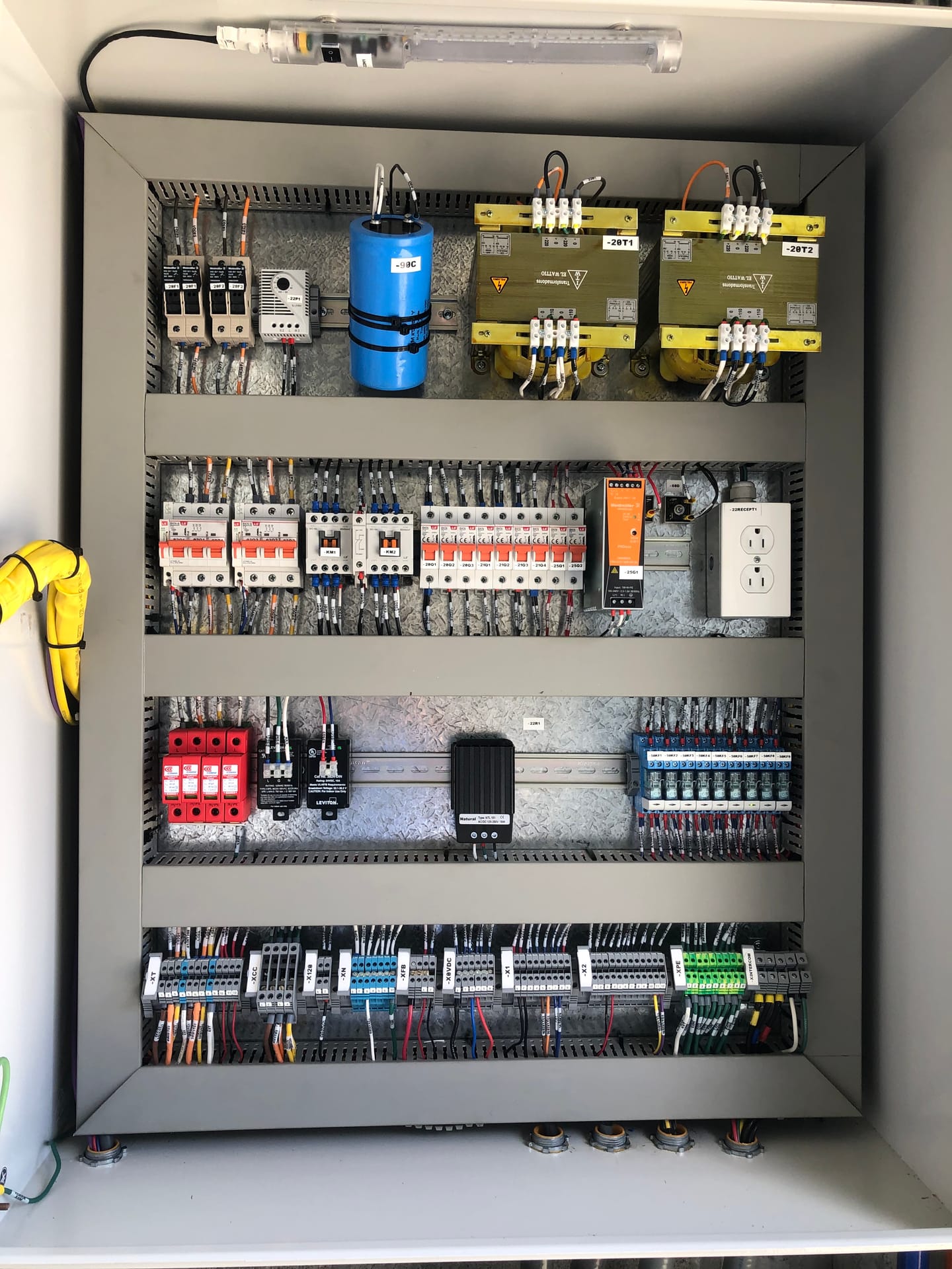 Interior de un segundo tablero de control, con la acometida en canaleta amarilla, los transformadores de mando arriba y las borneras de señales abajo.