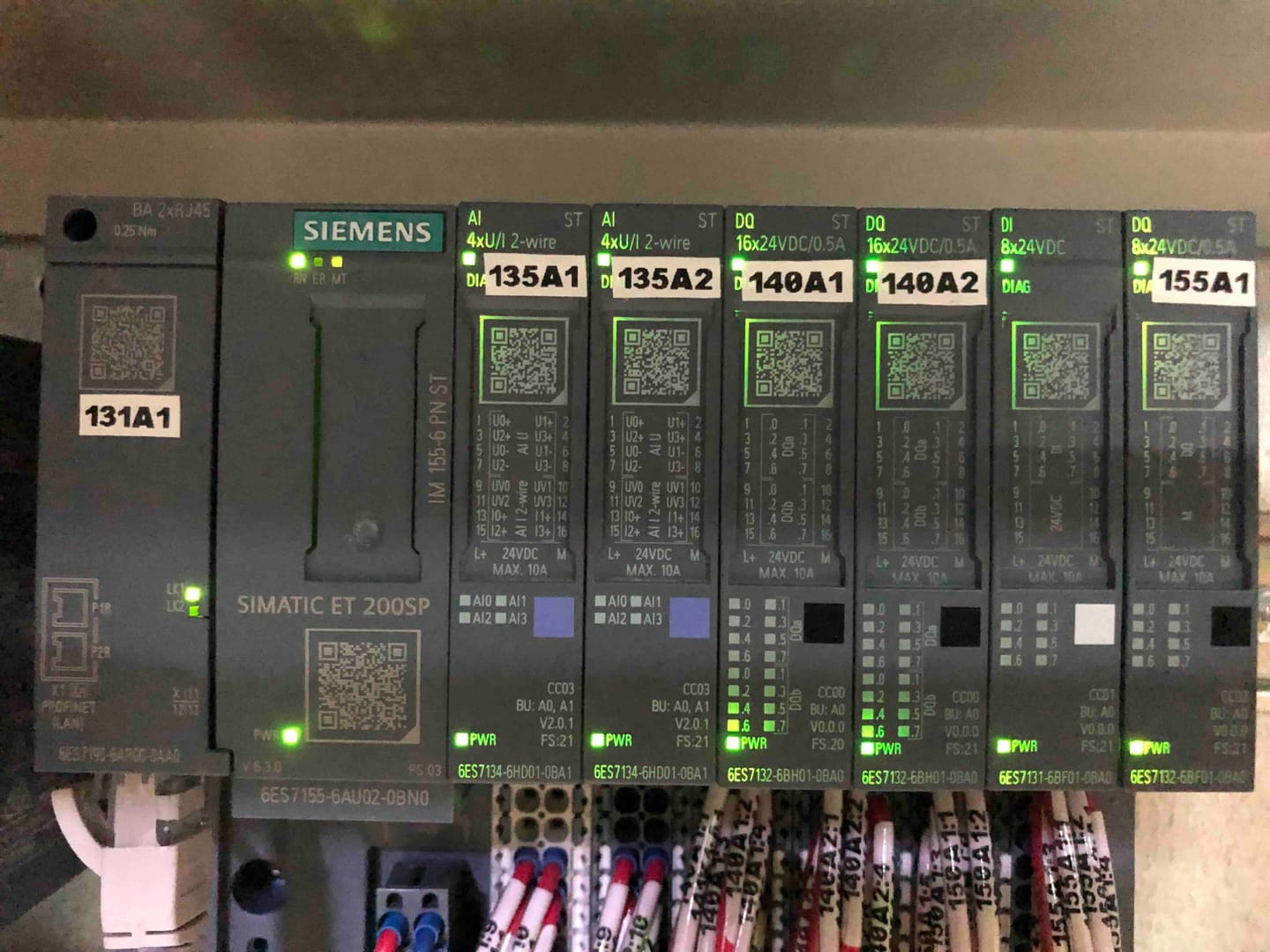 Módulos SIMATIC ET 200SP rotulados sobre riel, con sus entradas y salidas conectadas y el cableado marcado circuito a circuito.