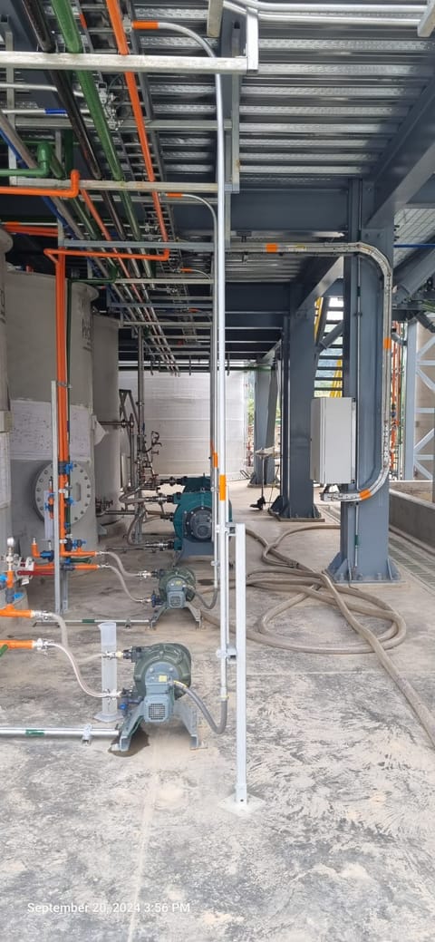 Canalización eléctrica y tubería de proceso en obra, junto a una columna estructural.